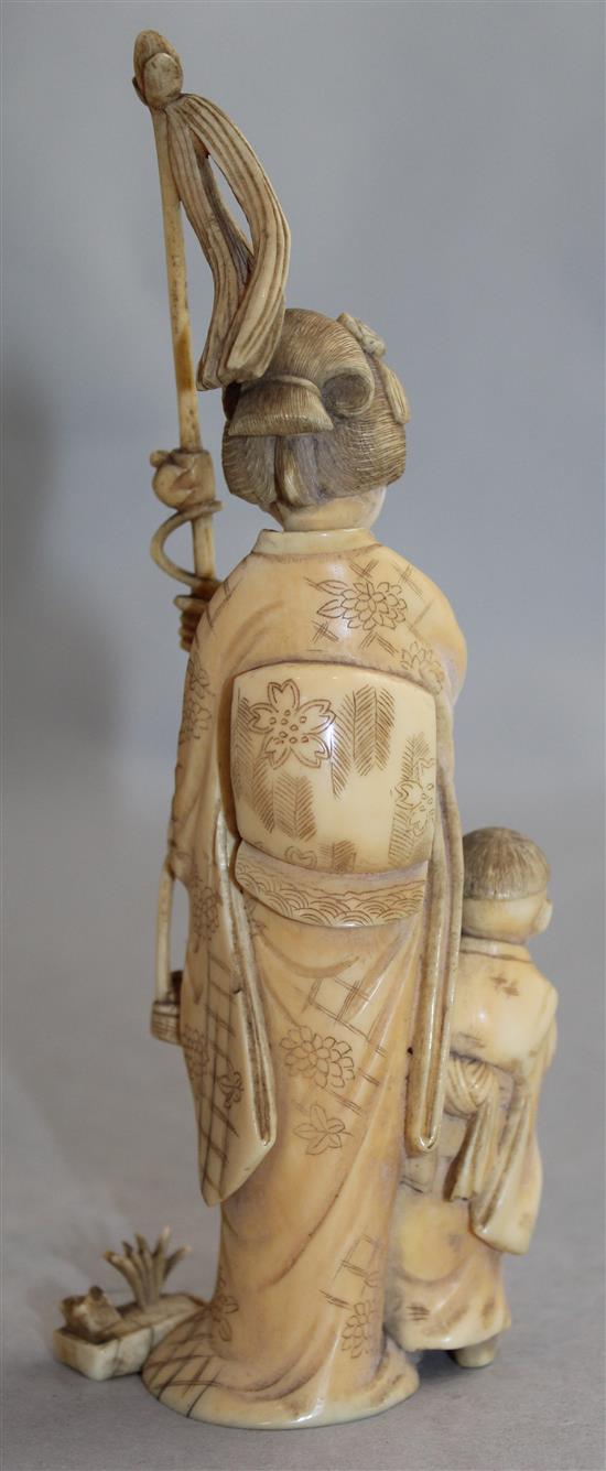 A Japanese ivory group of a woman carrying a basket of pomegranates, Meiji period, 16.8cm